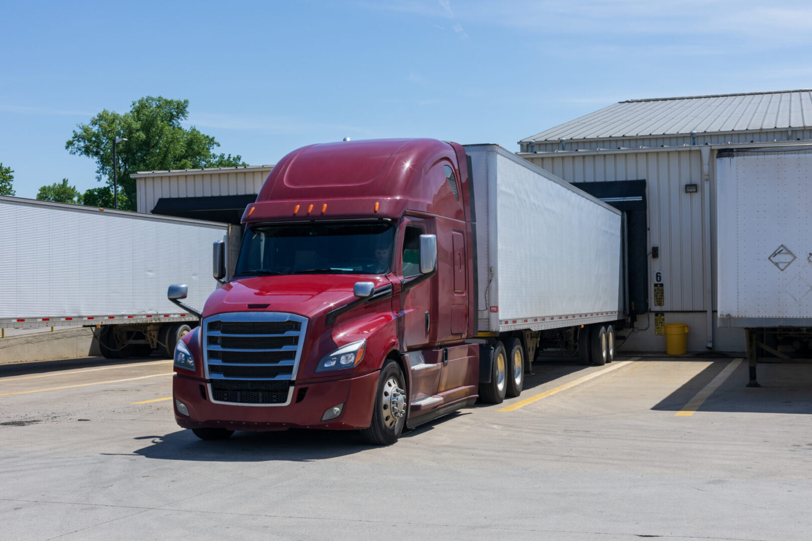 A red semi truck parked in front of a white building.